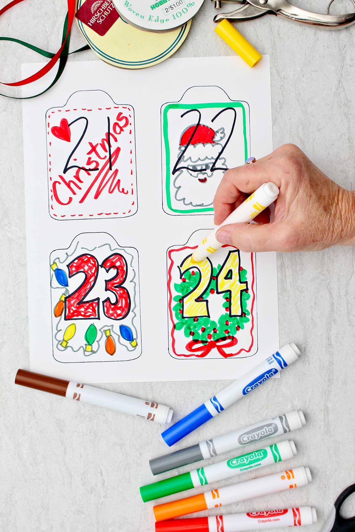 Person coloring in the number 24 in yellow with other completed cards ready to be cut out.