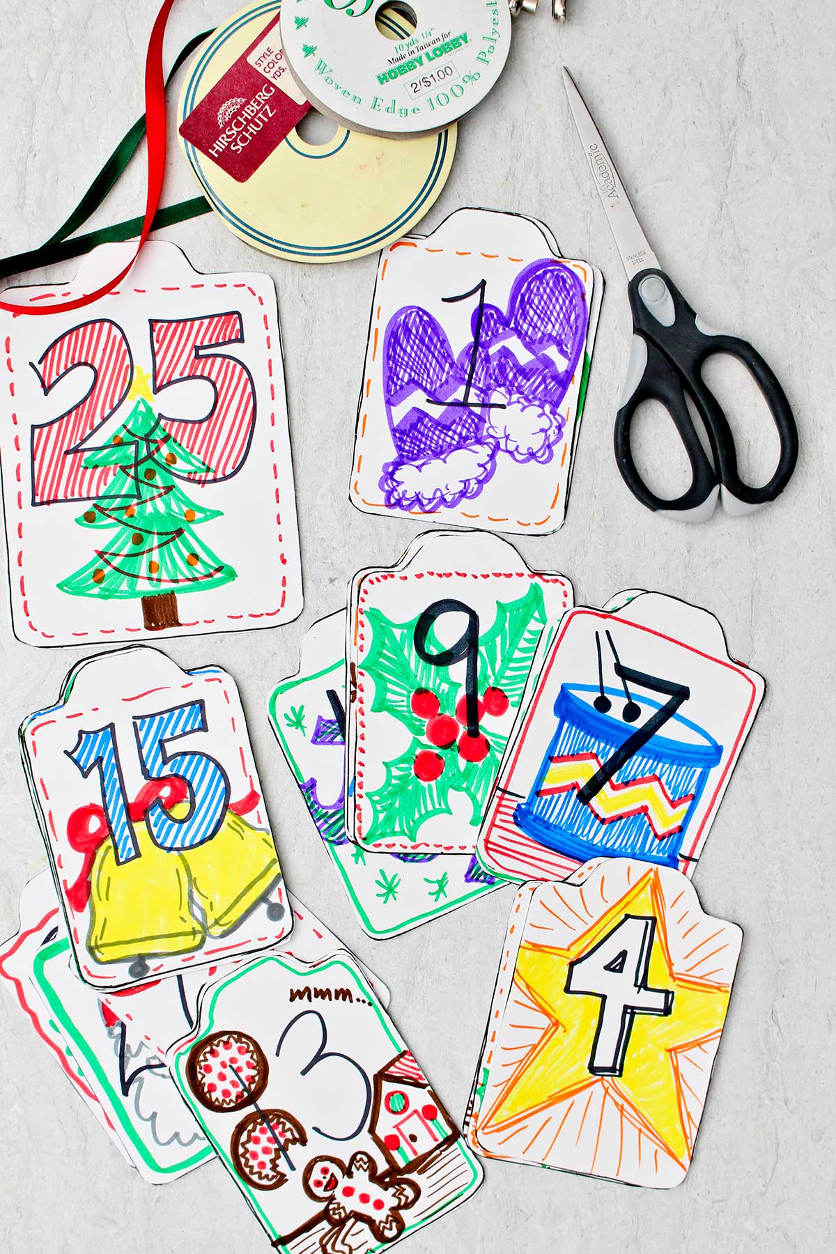 A collection of kindness cards with numbers and colorful festive drawings on them with scissors and ribbon near by.