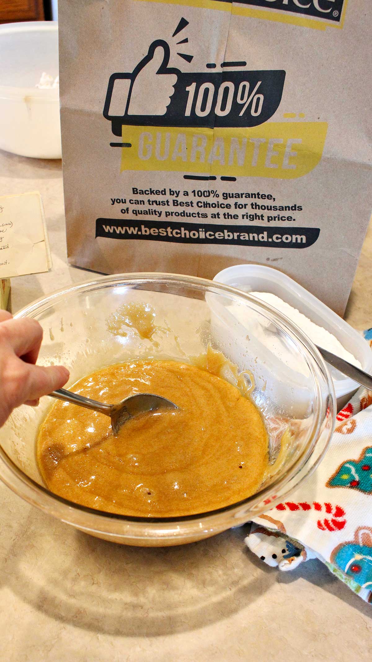 Person stirring a bowl of caramel with paper bag and linen in the background.