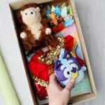 Person holding a stuffed Bluey toy with a memory box filled with children's treasures in the background.