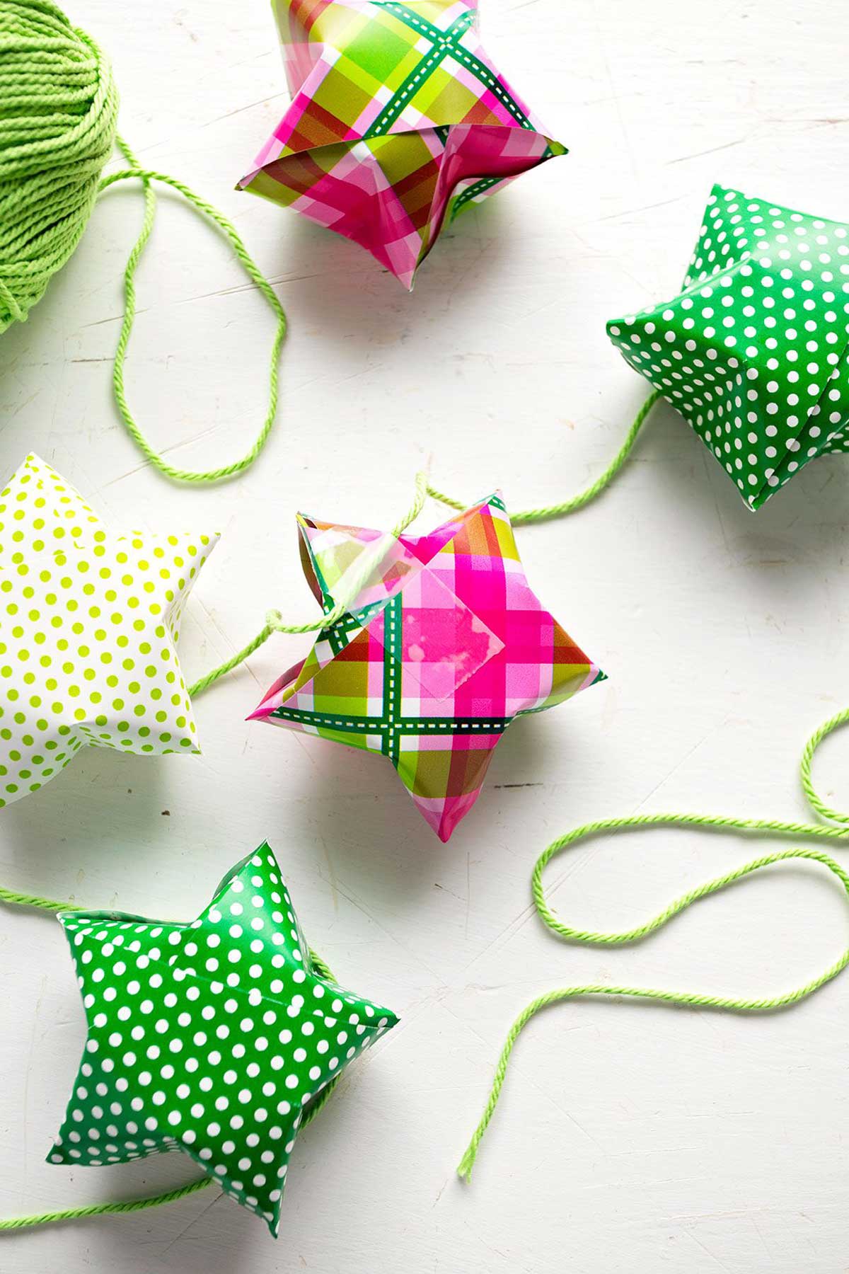 Large paper stars folded from colorful wrapping paper, attached to string to hang as a garland