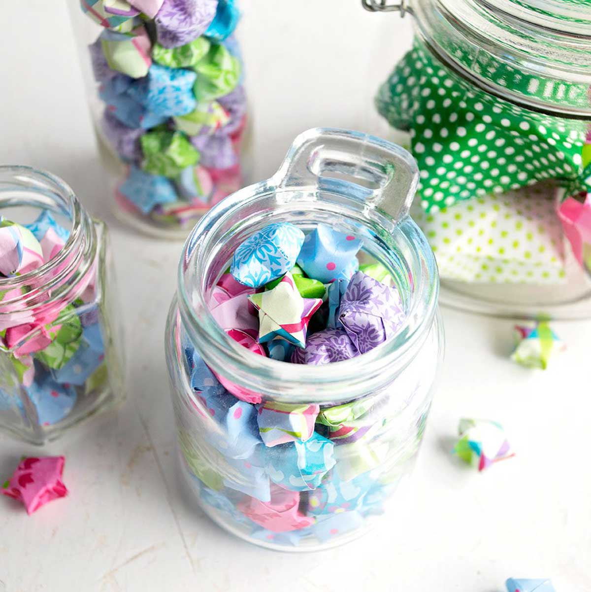 Colorful folded paper stars made from origami or scrapbook paper, added to glass jars