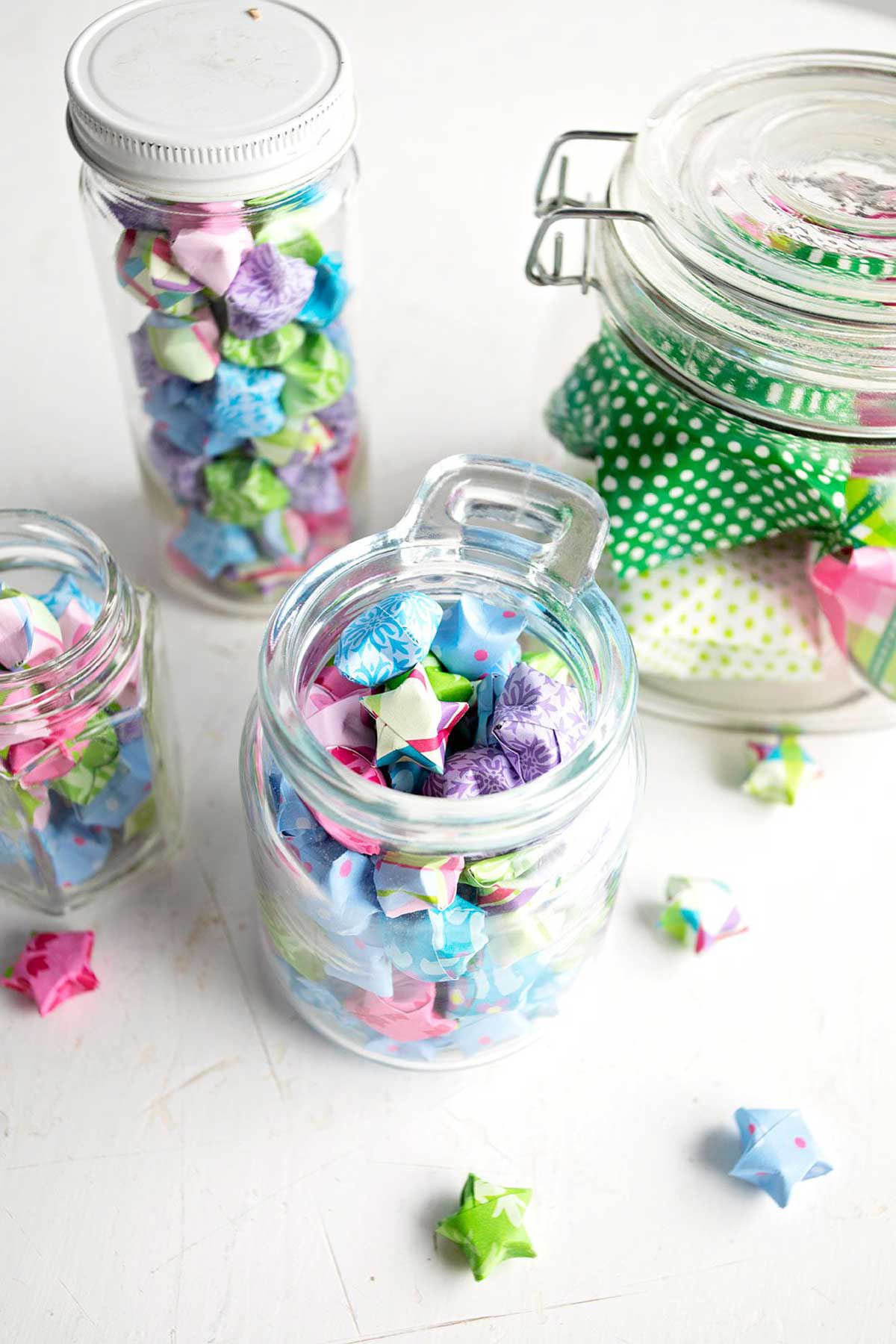 Colorful folded paper stars made from origami or scrapbook paper, added to glass jars