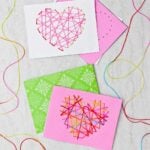 Two stitched Valentines Day cards made from pink, white and green paper and multi colored string.