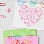 Two Valentines with heart shaped colorful paper clips attached to them.