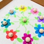 Close up view of the flower circle with wooden beads in the center of each flower, resting in the holes.
