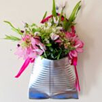 A completed upcycled tin can flower vase filled with pink flowers and greenery.