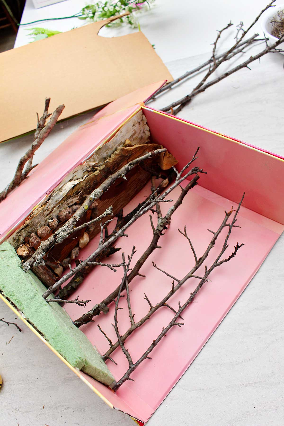 Twigs, bark, rocks and a piece of foam show the beginnings of a miniature forest book nook shelf insert.