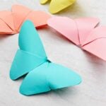 Four origami butterflies in pastel shades of blue, yellow, orange and pink.