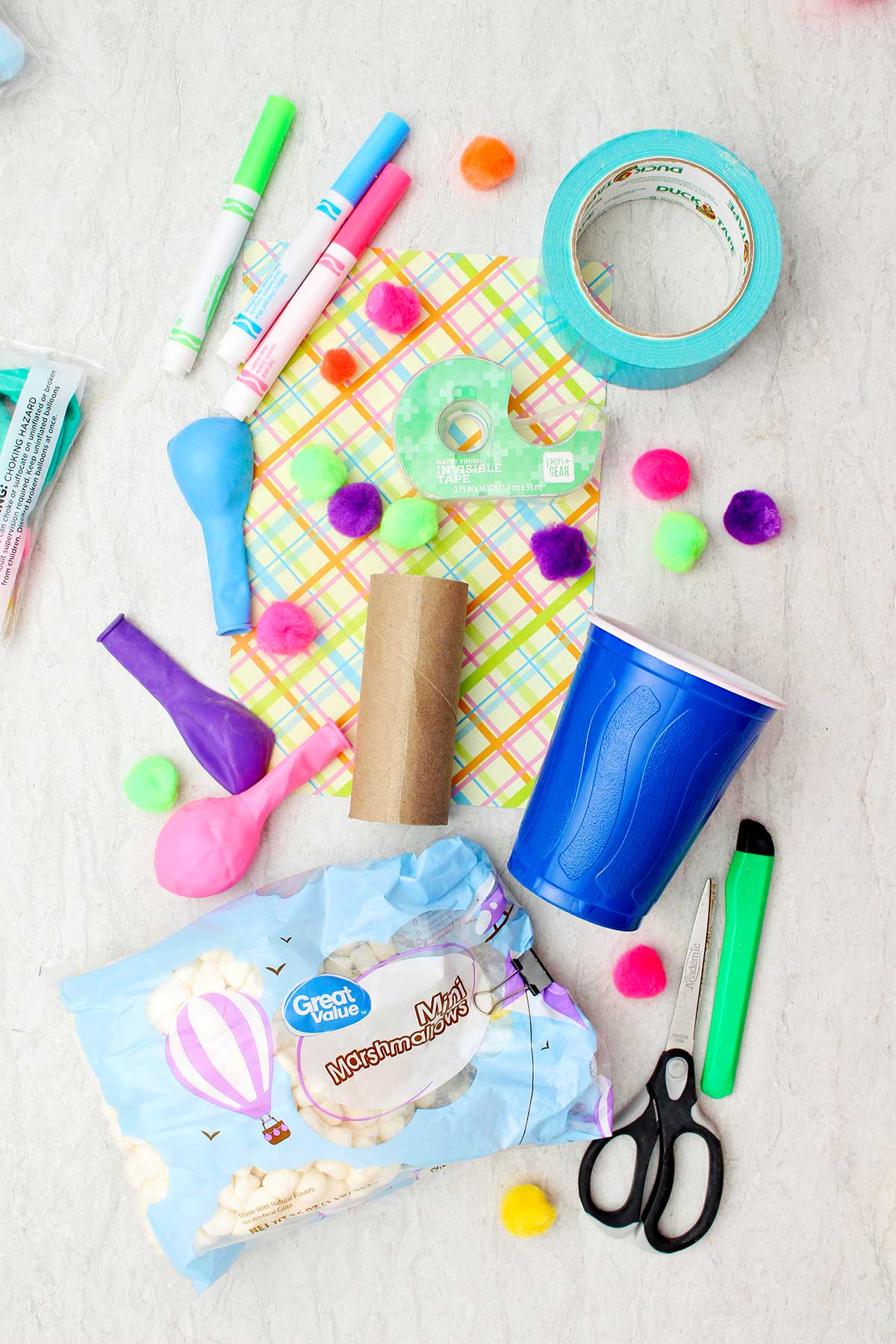 Colorful pom poms, plastic cup, toilet paper roll, tape, markers, balloons and mini marshmallows.