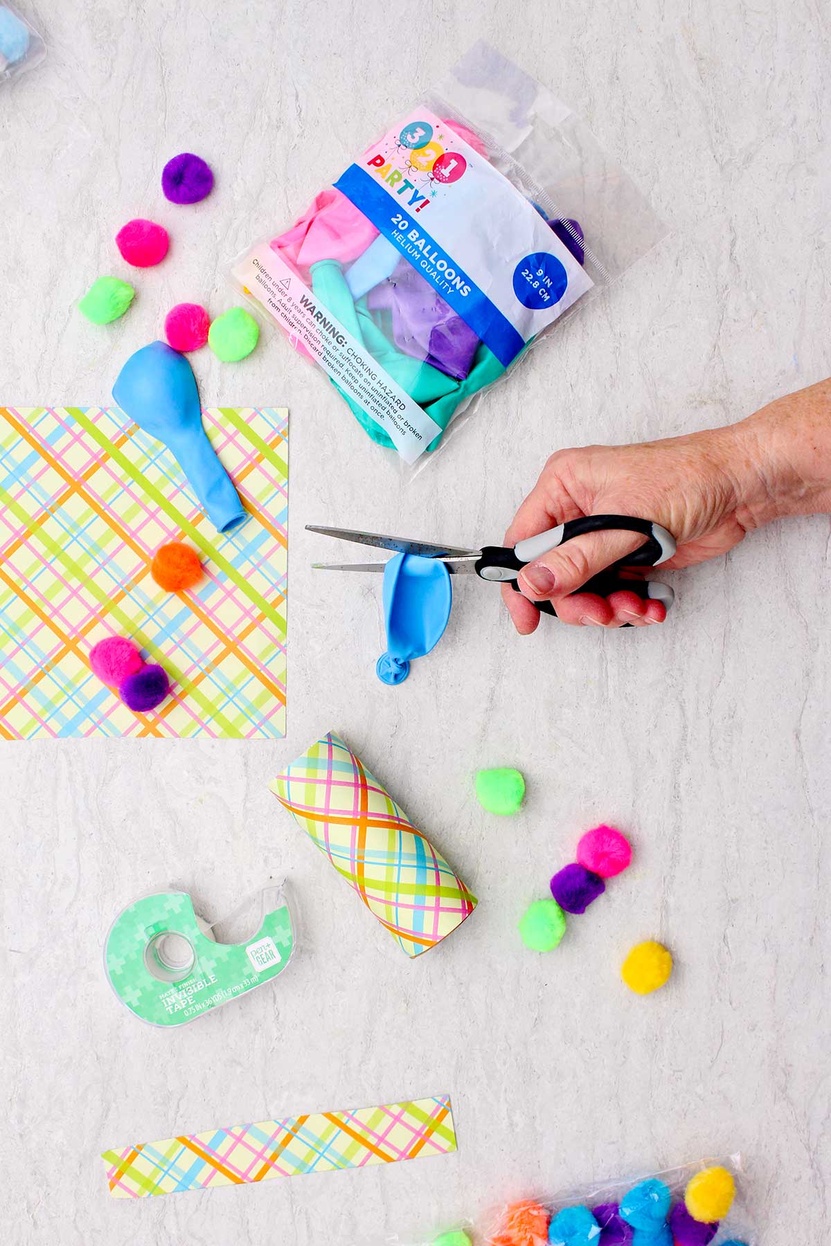 Person cutting blue balloon with other supplies near by.