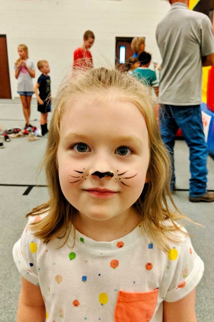 Young girl with black cat face painting.
