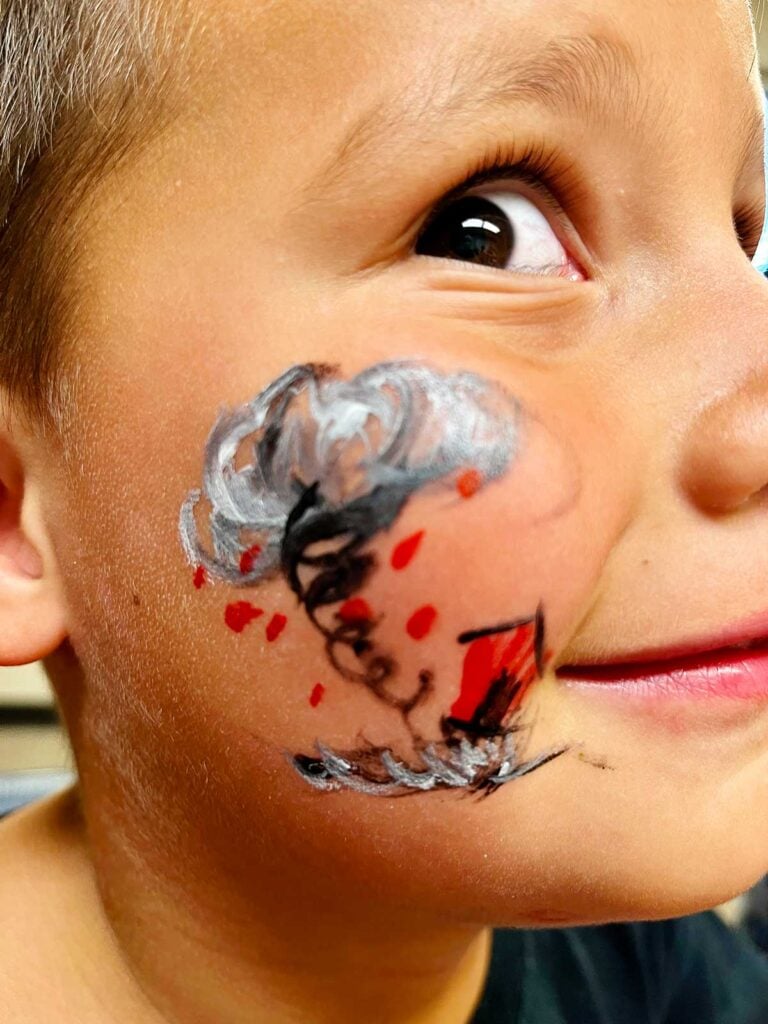 Young boy with brown eyes close up of tornado face painting.