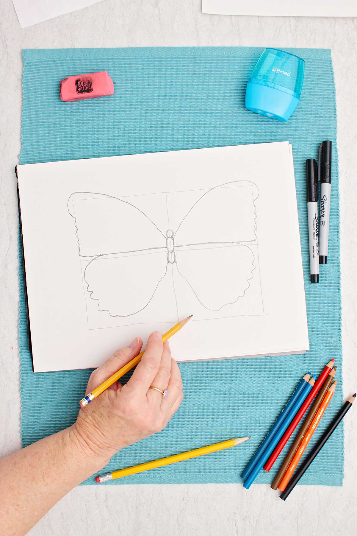 Person sketching the four quadrants of a butterfly drawing.