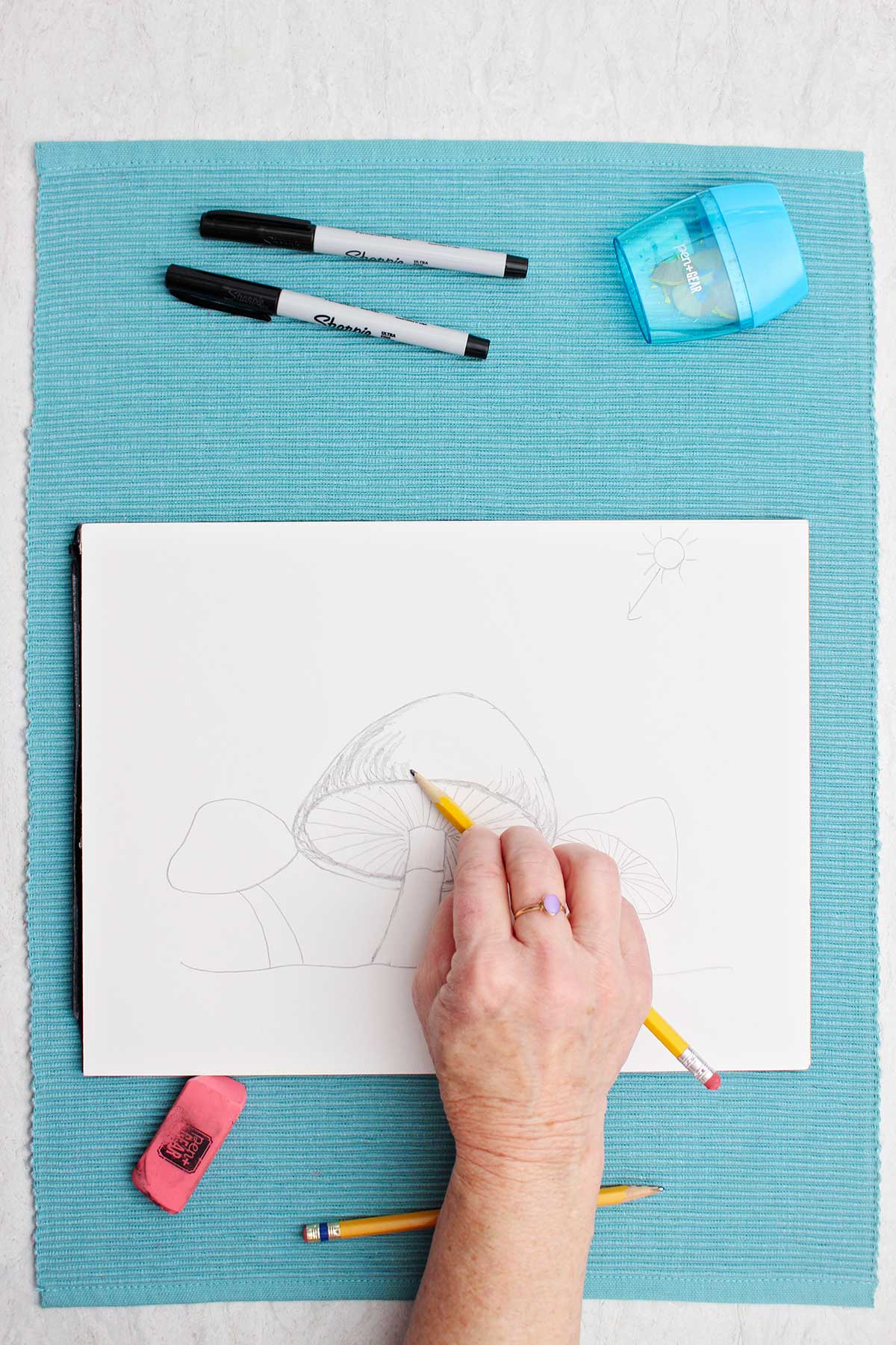 A pencil drawing of a mushroom, the artist adding the shadow