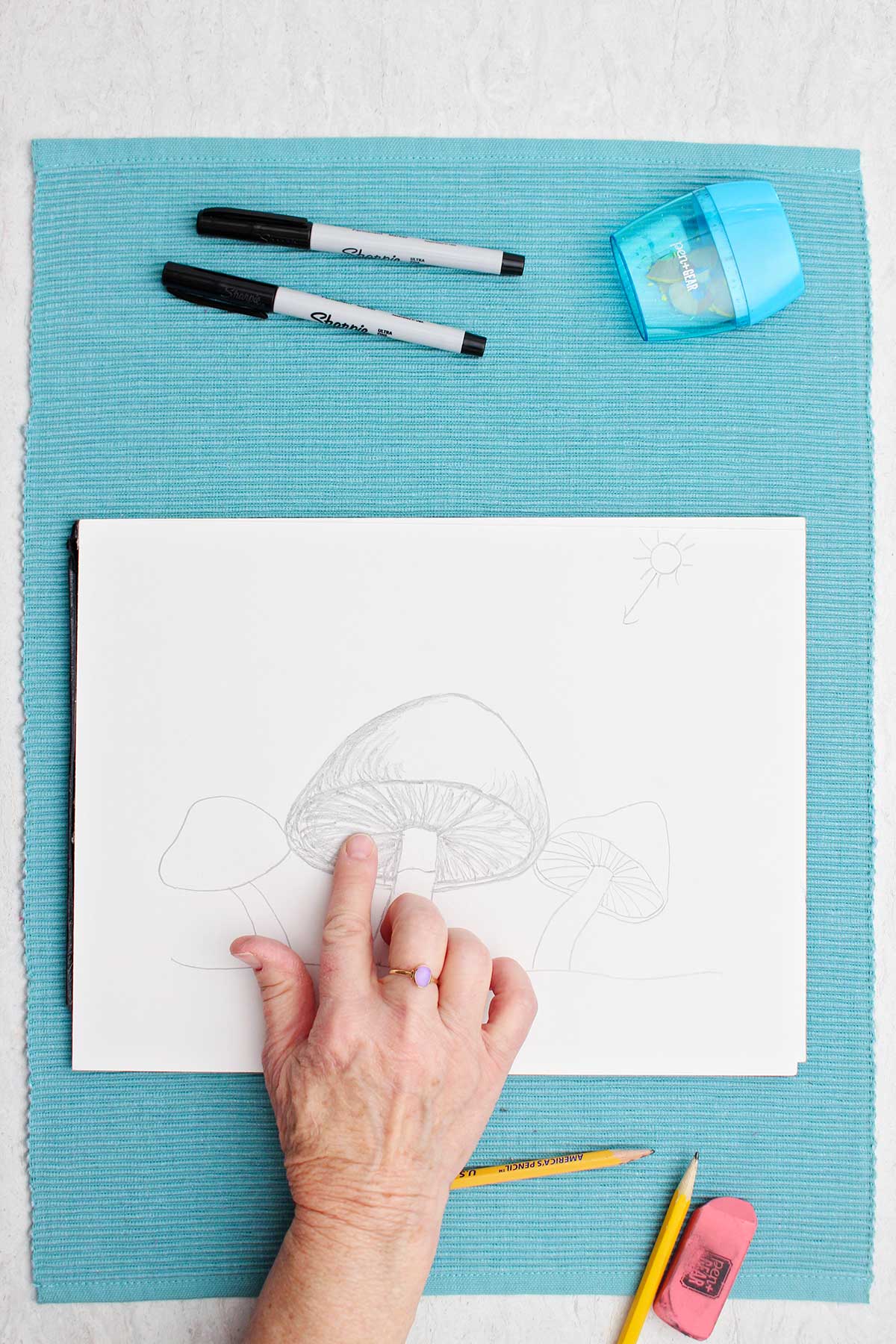 A pencil sketch of a mushroom, the artist smudging the shadow