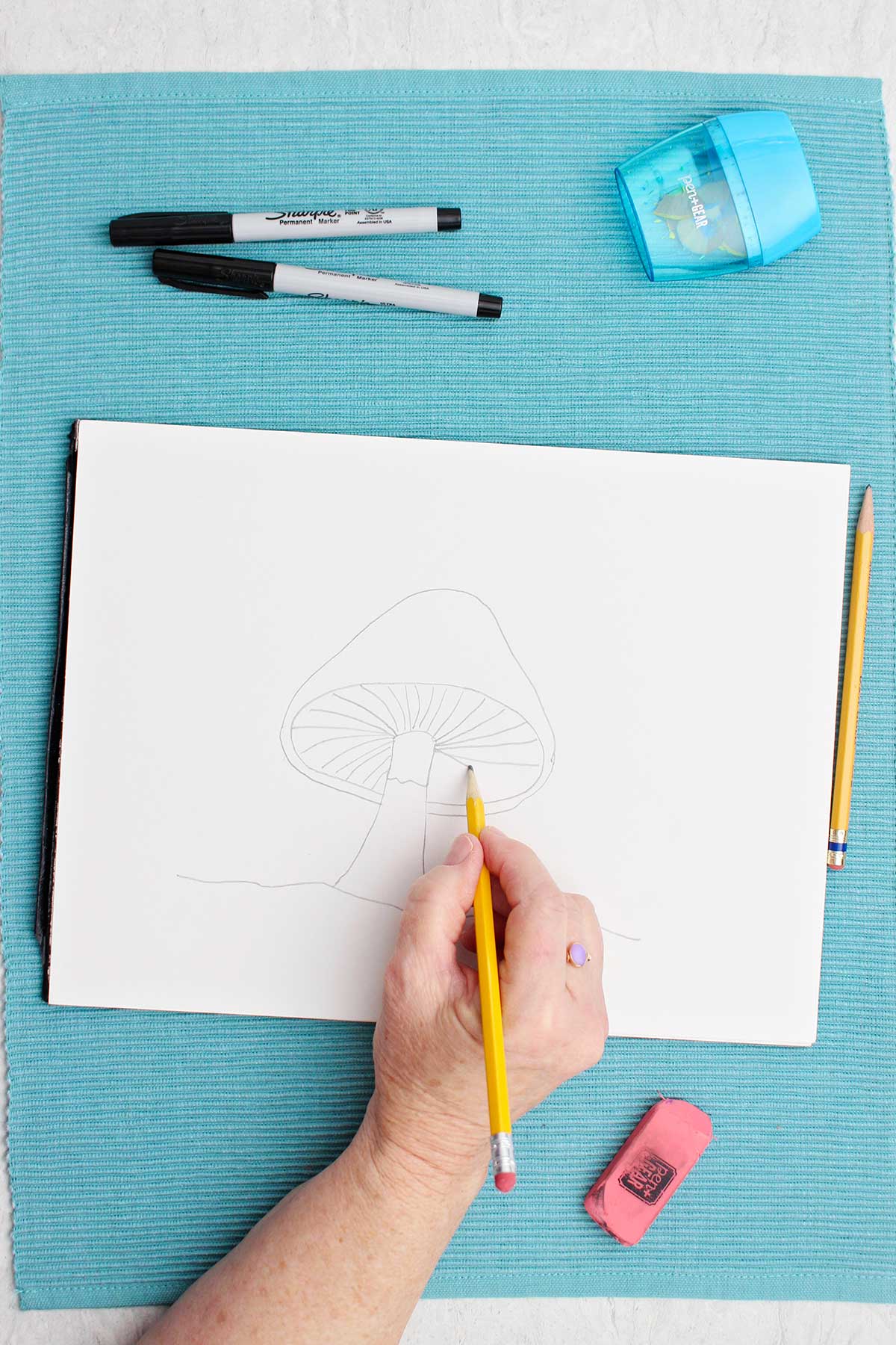 A person sketching a mushroom on a piece of paper