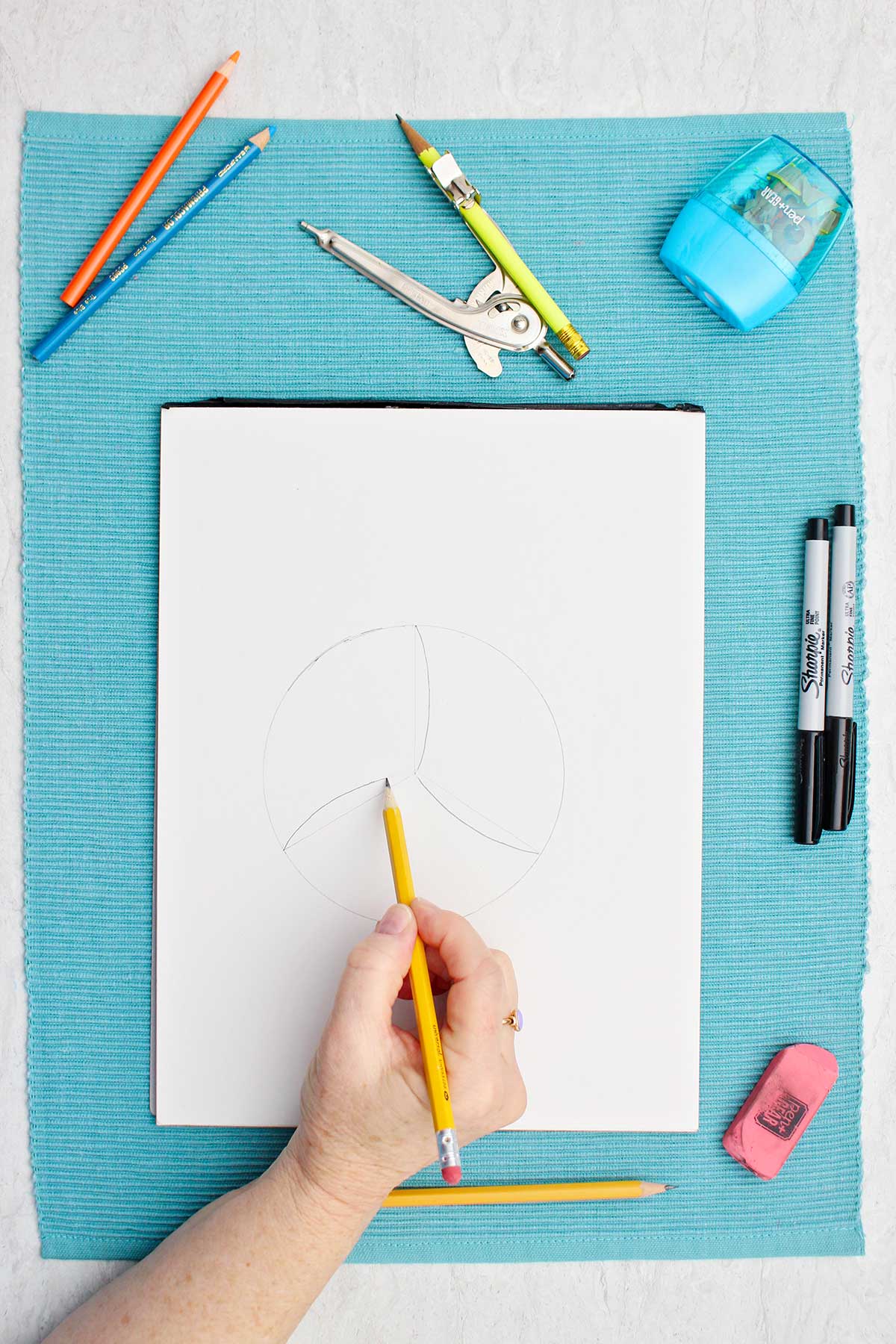 Person sketching detail lines on volleyball drawing with pencil.