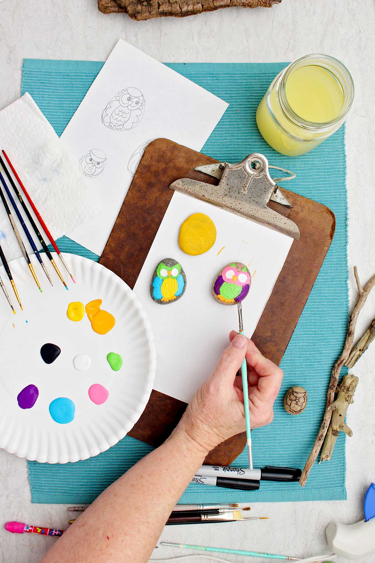 Person painting purple wings on a painted owl rock.