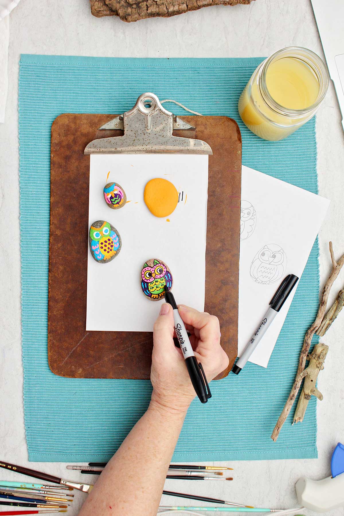 Person outlining painted owl with sharpie marker.