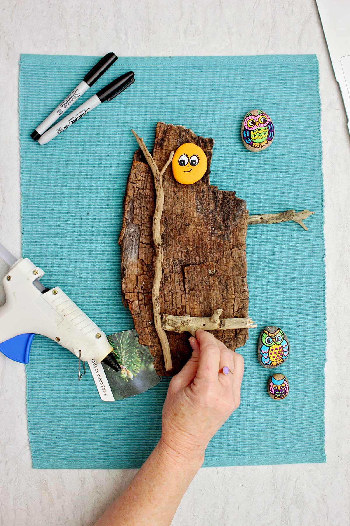 Person gluing down small branches on a piece of wood.