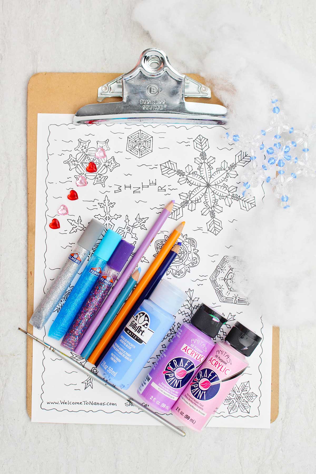 Supplies for coloring and painting the free printable snowflake coloring page as well as some fake fluffy snow for decoration.