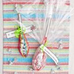 Two completed and wrapped whisk candy gifts wrapped in cellophane with little notes tied on.