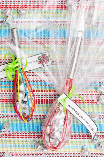 Two completed and wrapped whisk candy gifts wrapped in cellophane with little notes tied on.