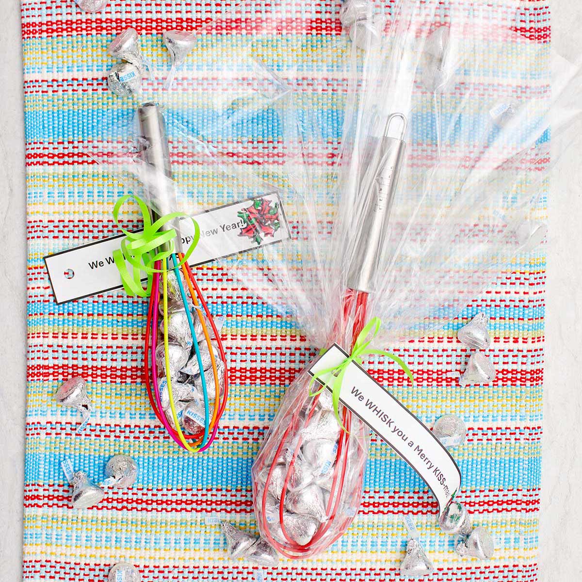 Two completed and wrapped whisk candy gifts wrapped in cellophane with little notes tied on.