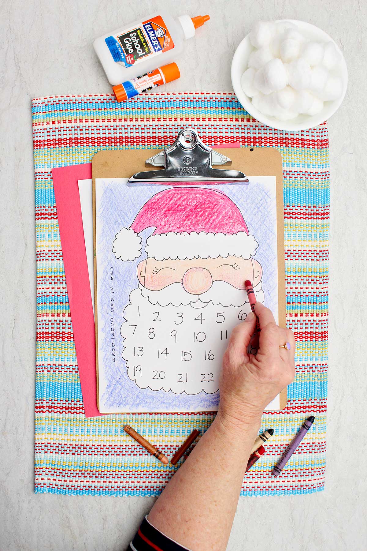 A person coloring Santa's cheeks a little rosy with a red crayon.