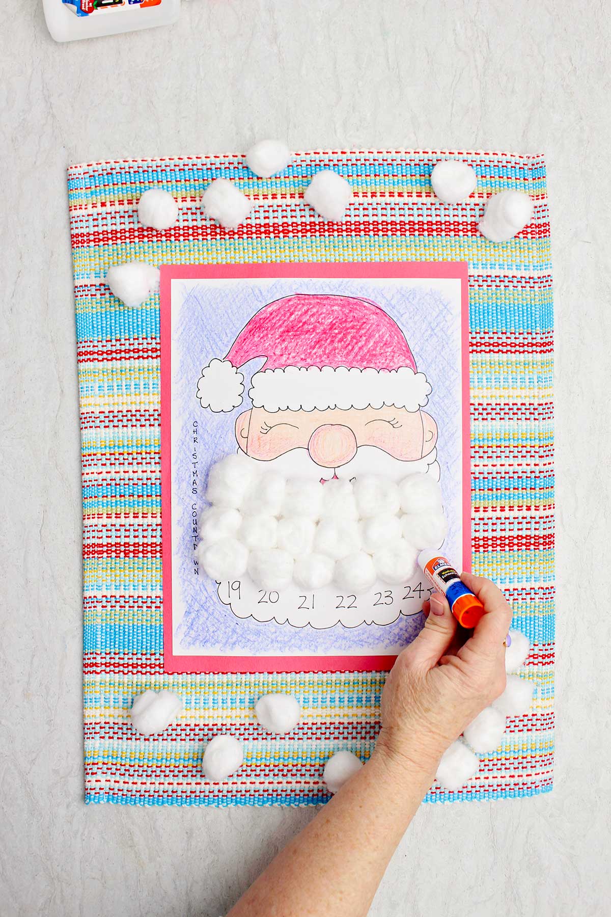 A person putting some glue on a day on Santa's beard in the calendar countdown.