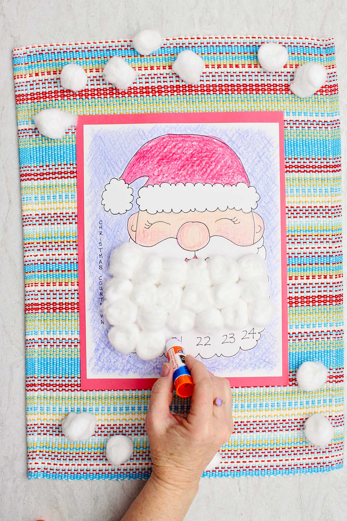A person putting some glue on a day on Santa's beard in the calendar countdown.