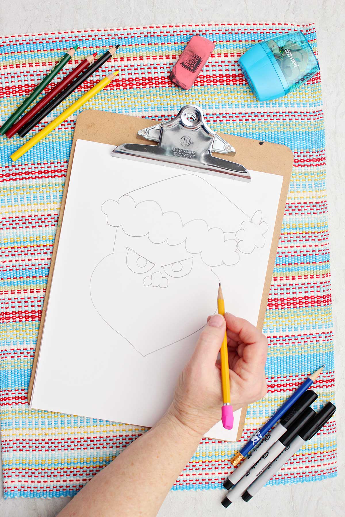 Person adding eyes and a nose to their Grinch sketch.