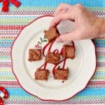 A person picking up a piece of fudge off of a holiday plate.