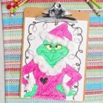 Completed Grinch colored printable complete with cotton ball accents clipped into a clip board.