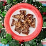 A red rimmed plate of toffee surrounded by festive ivy.