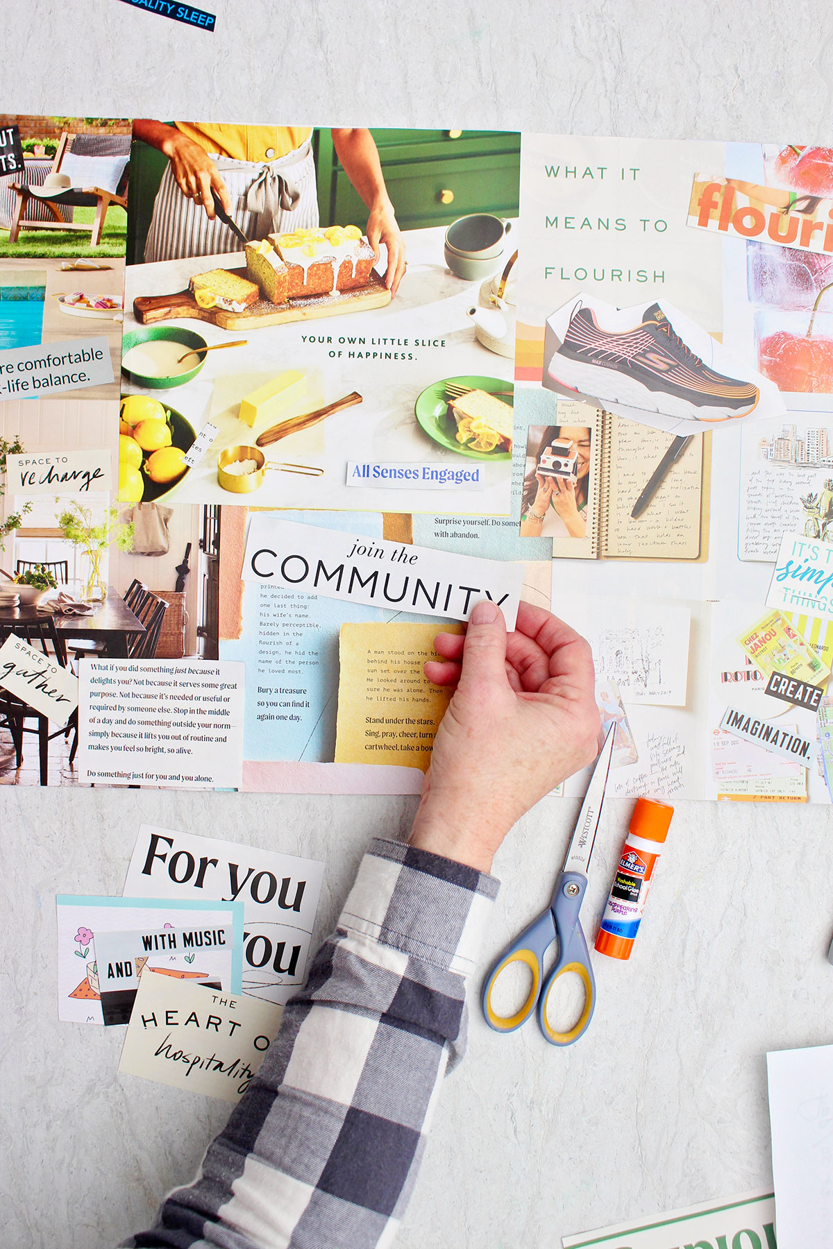 A person sticking a magazine cut out that says "join the community" on their vision board.