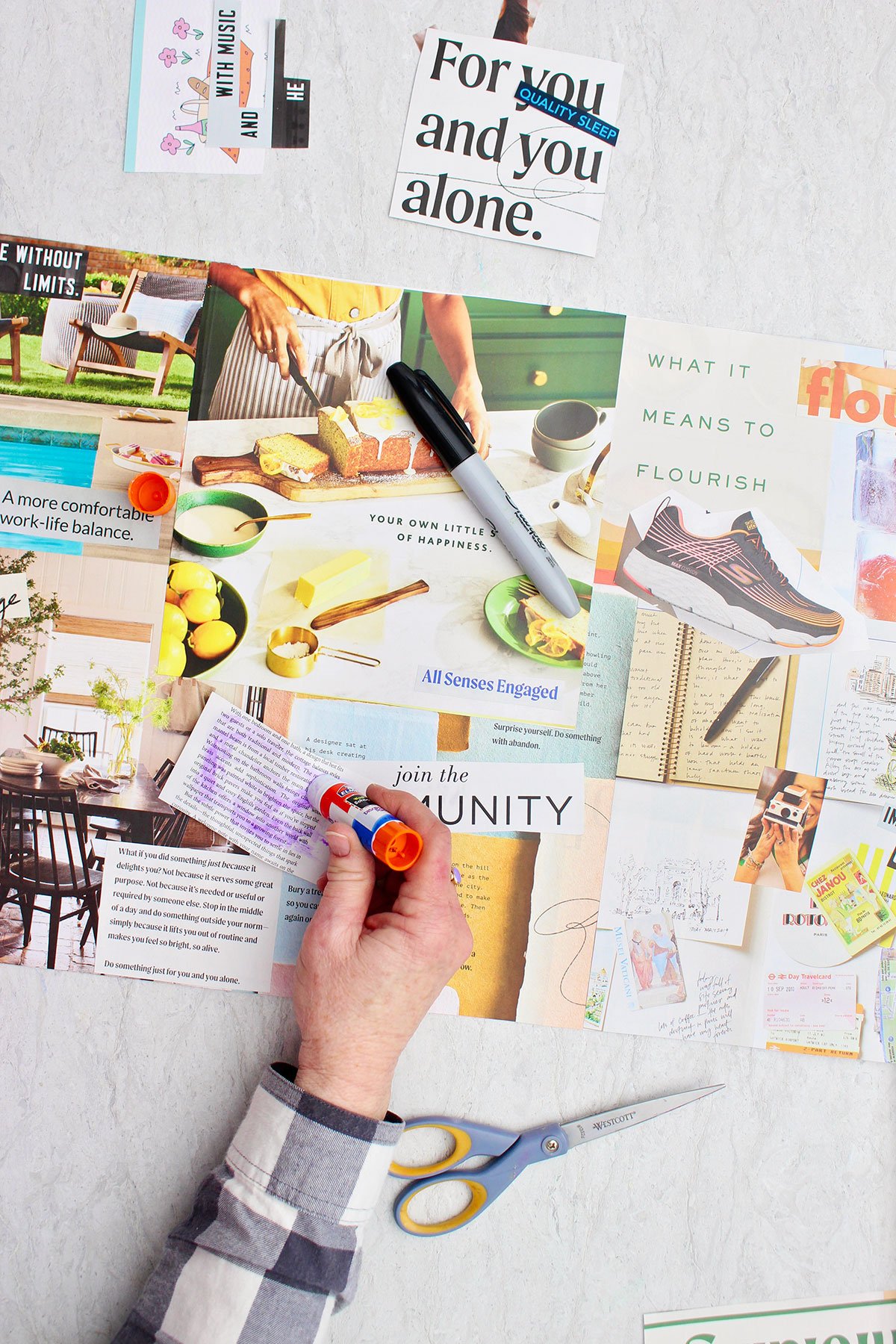 A person securing their magazine cut outs with a purple glue stick.