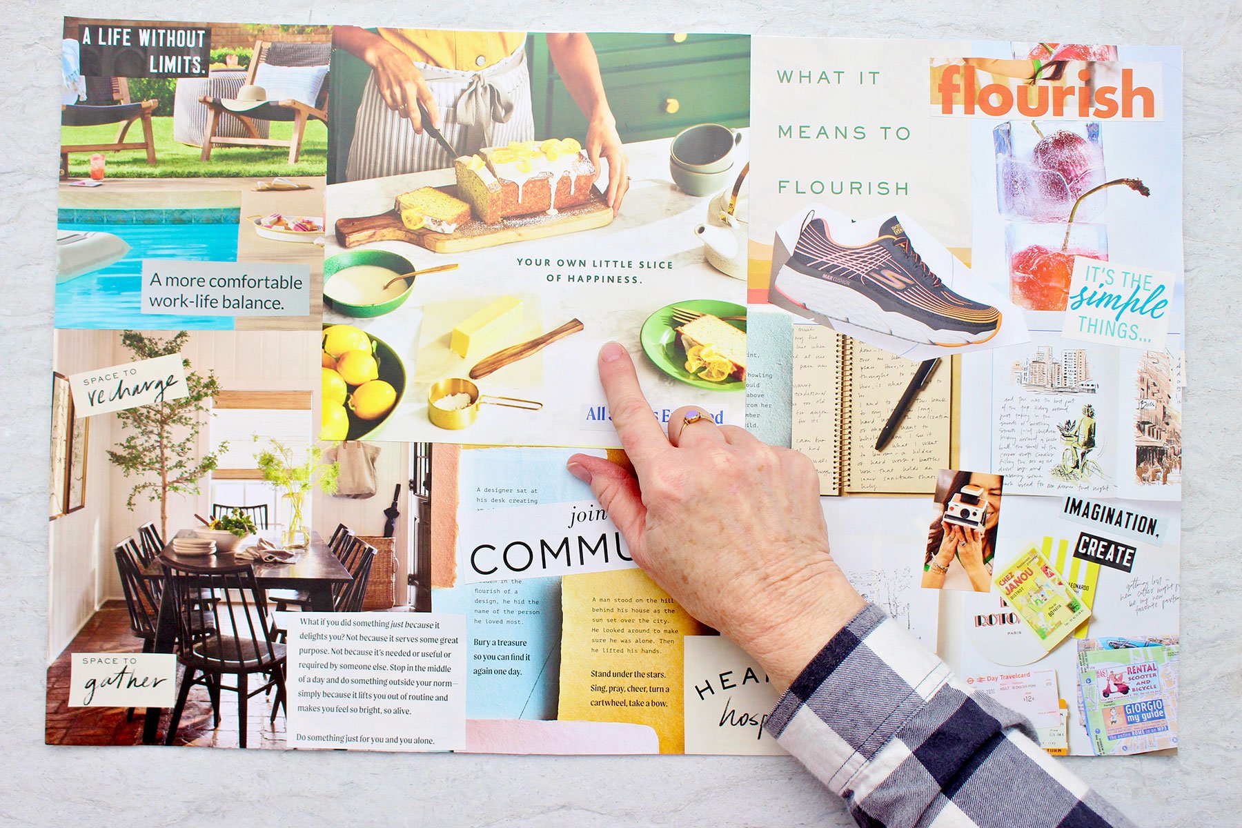 A vision board full of bright fresh colors with bold words and photos with a person pointing at a magazine cut out.