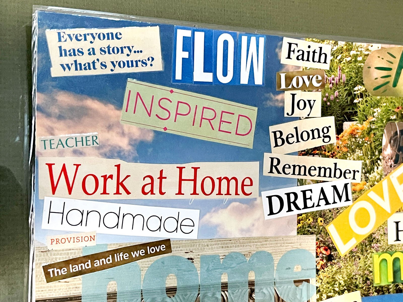 A close up of a magazine clipping vision board with bold text and bright colorful pictures of a sky and a garden.