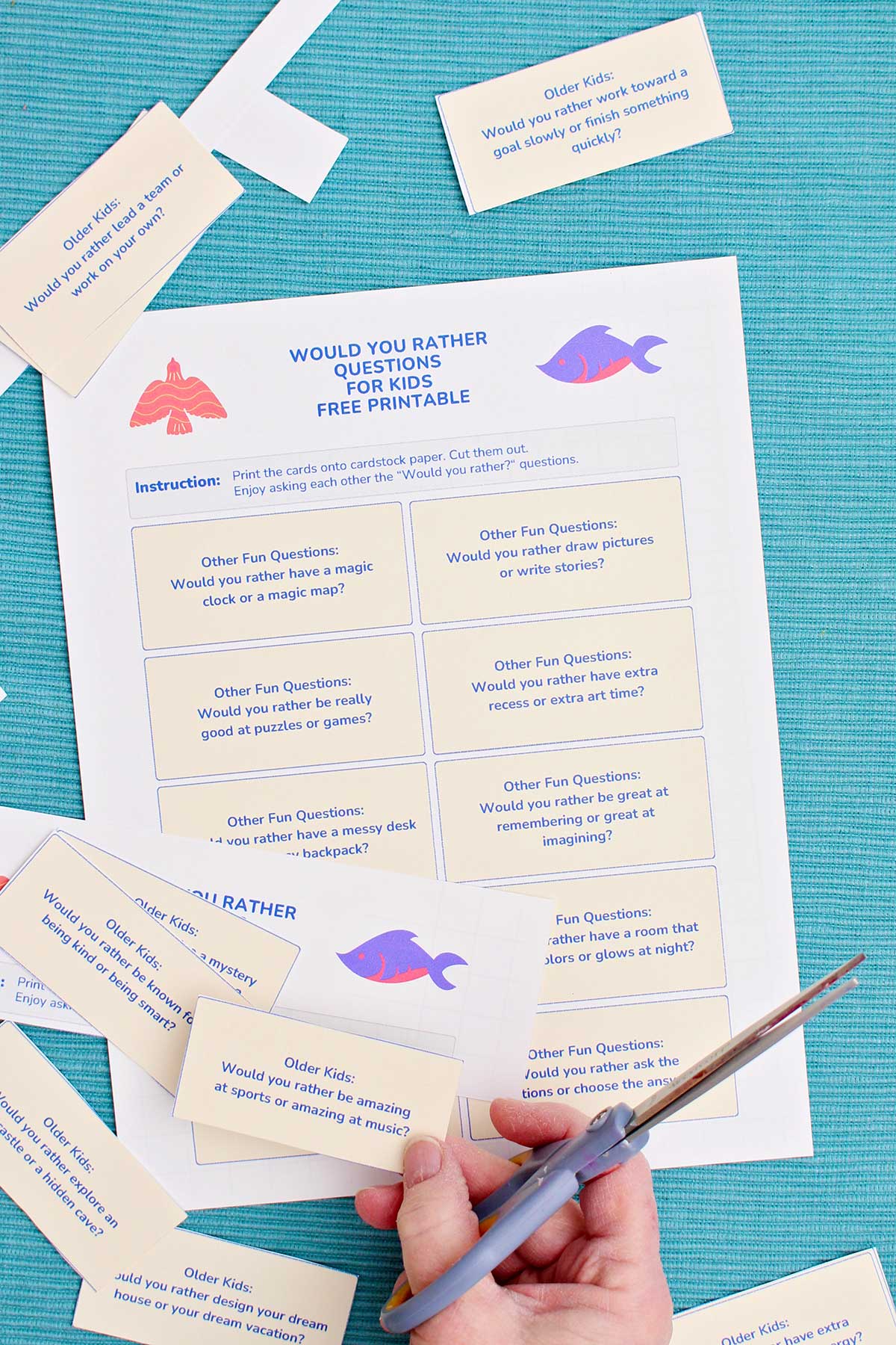 A printable with Would You Rather Questions being cut out with a pair of scissors