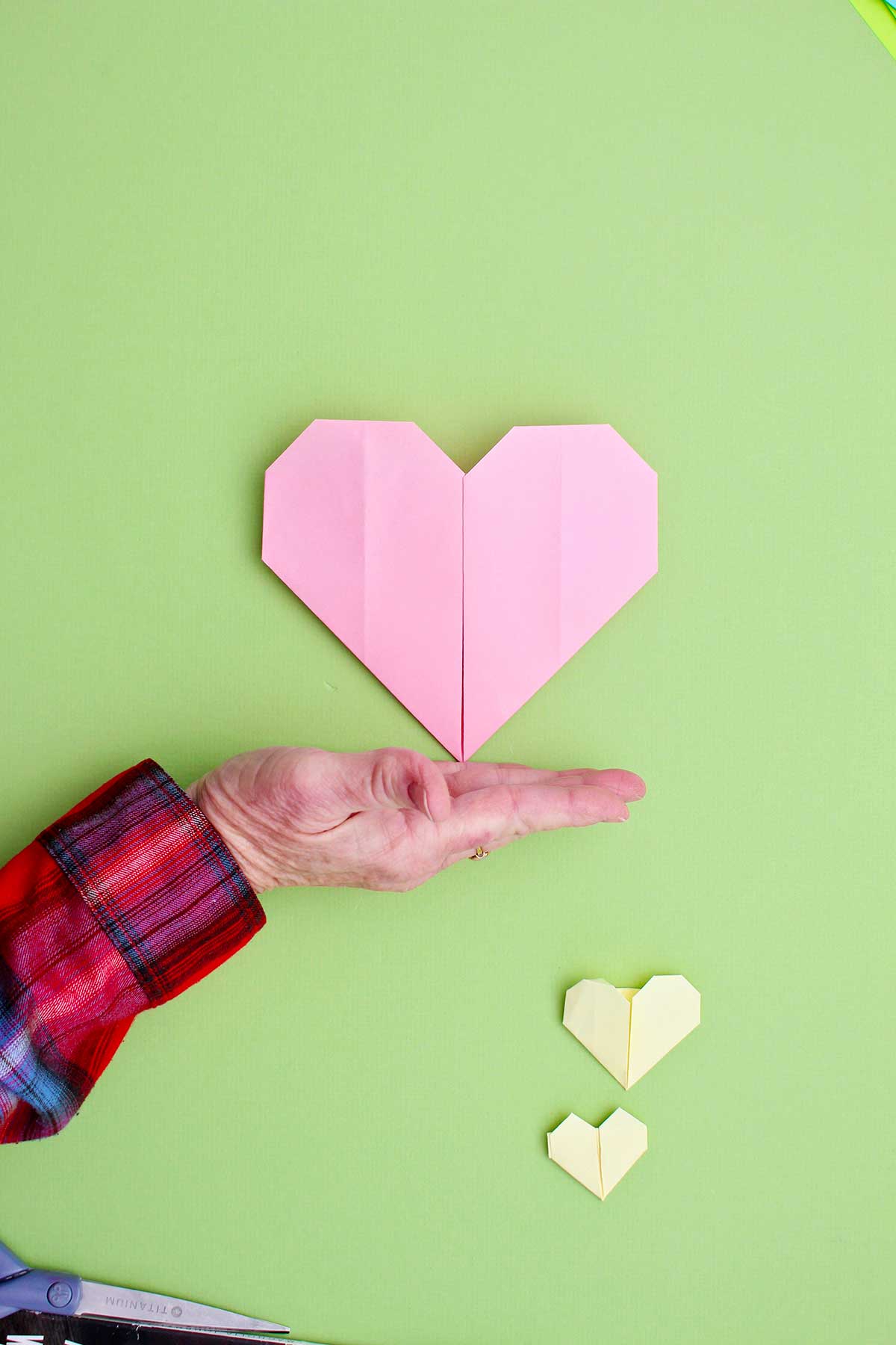 A person showing off their completed pink origami heart.