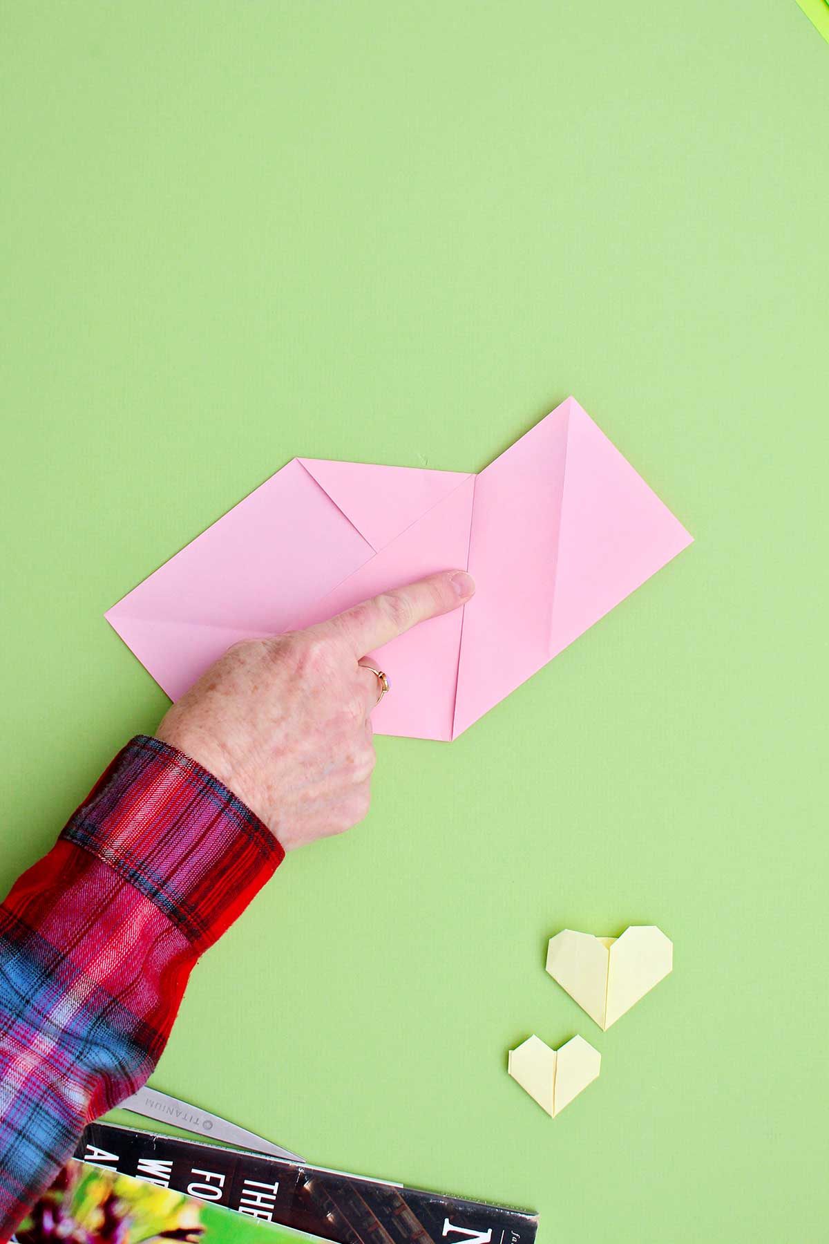 Person showing a center fold of a pink origami heart.