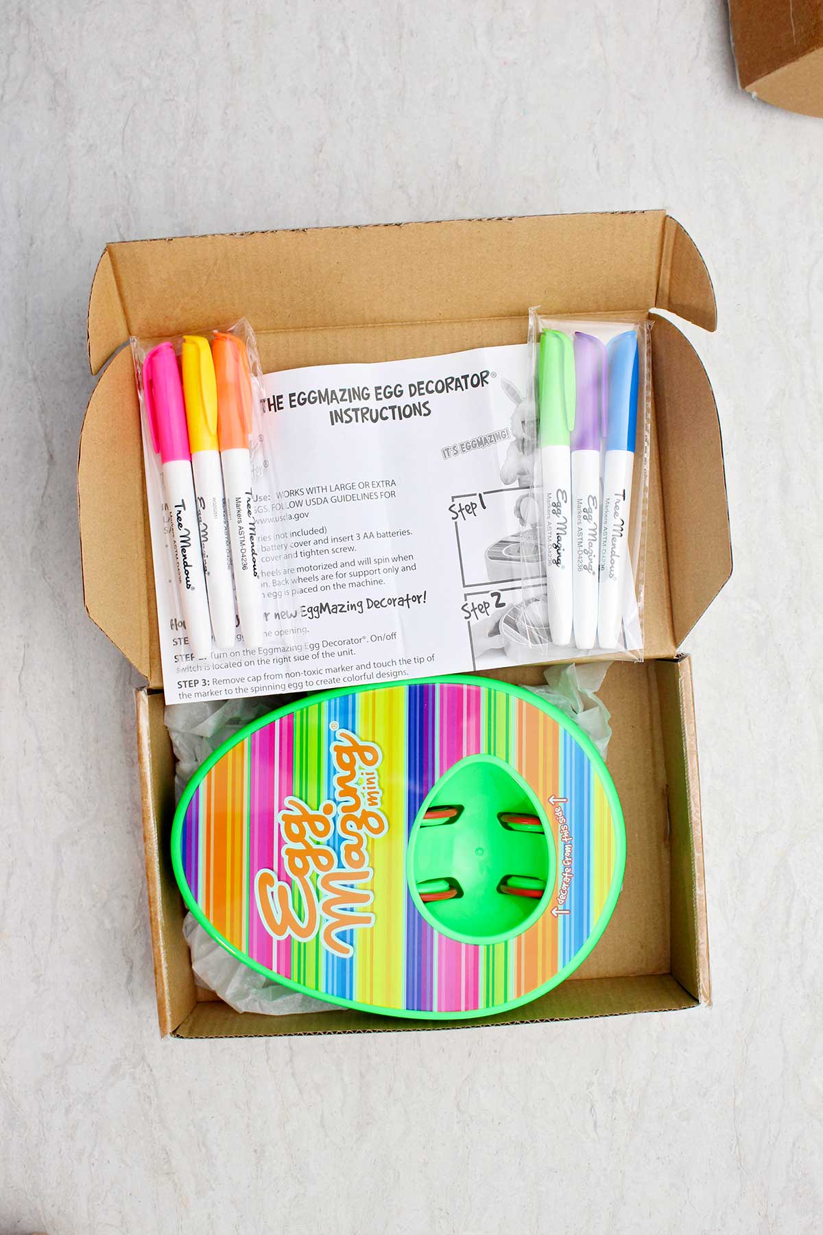 A box full of an EggMazing kit, markers and directions.