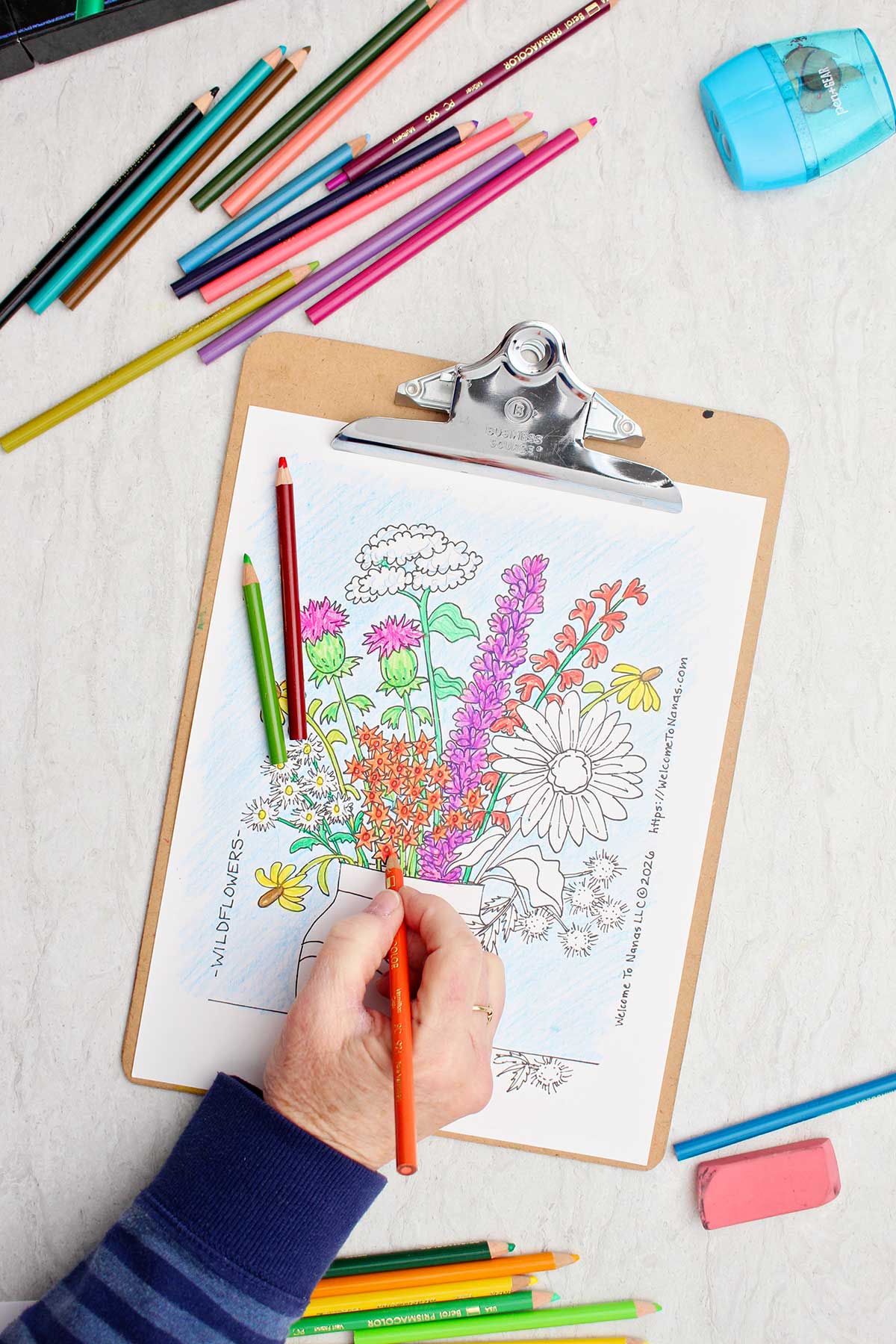 Person coloring tiny flowers orange in the coloring page of a bunch of wild flowers in a vase.