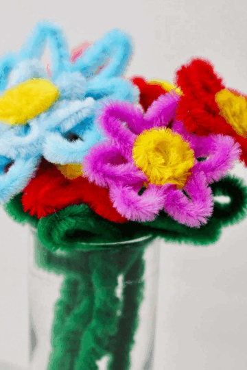 A close up of a pipe cleaner bouquet in a glass.