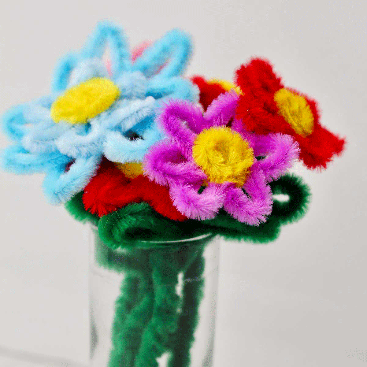 A close up of a pipe cleaner bouquet in a glass.
