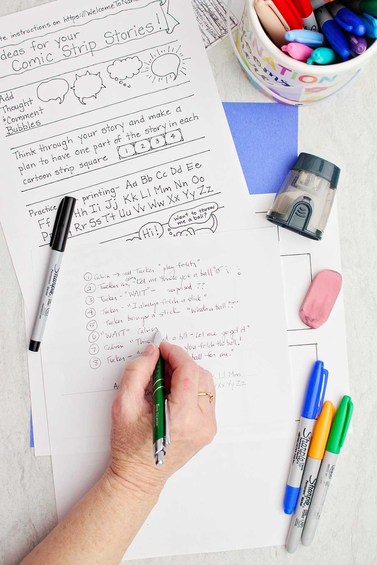 A person writing out the text on a white piece of paper for their comic strip story.