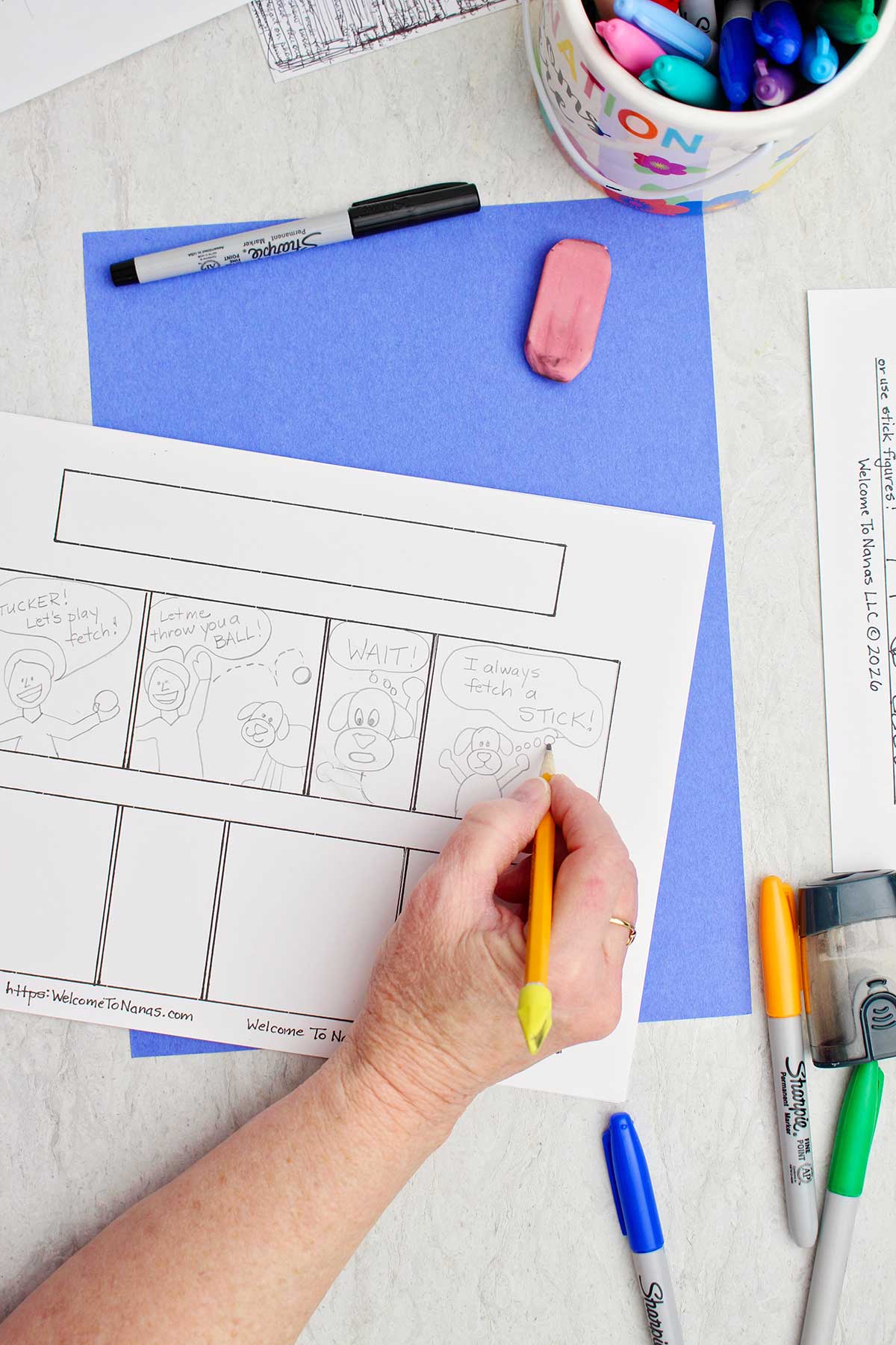 A person sketching out a story on their comic strip with pencil.