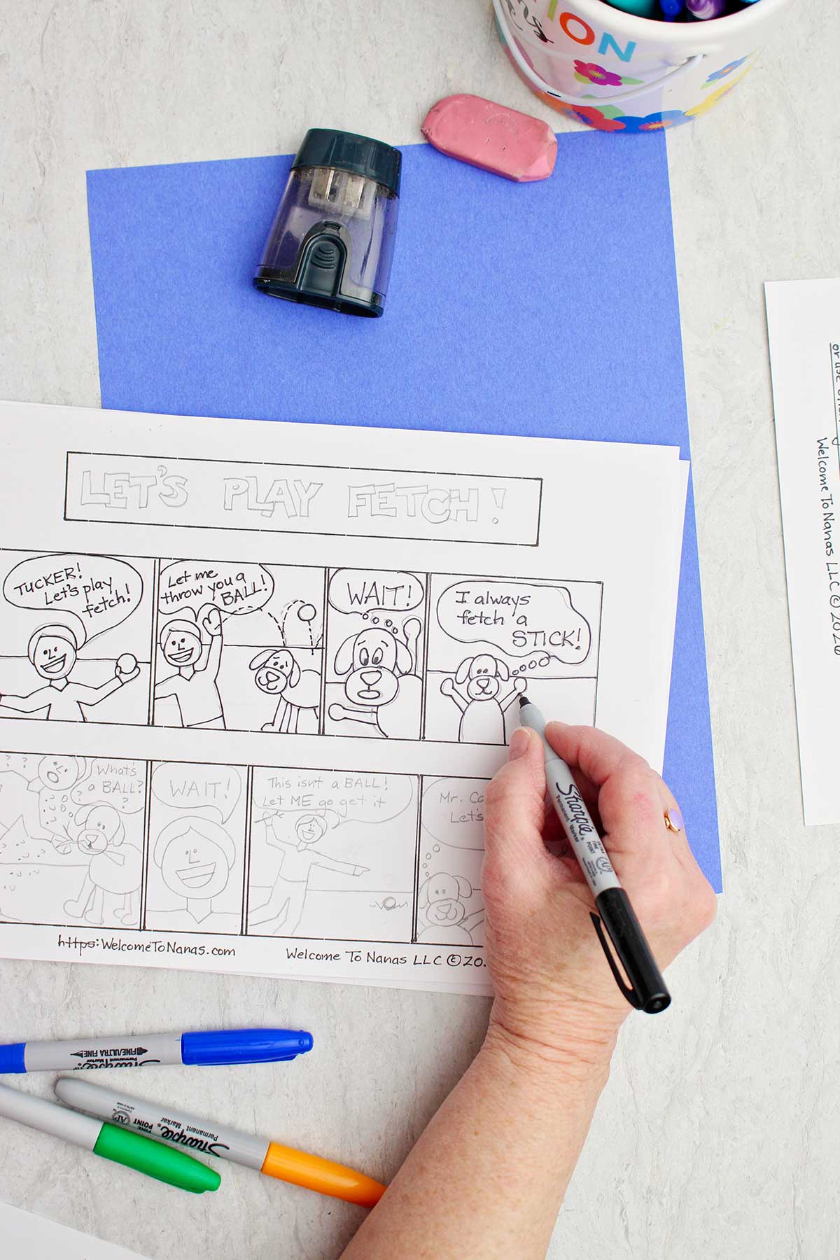 A person going over pencil with a sharpie in a comic strip about a boy and his dog.